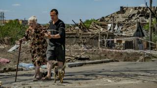 A man helping an old woman after a Russian airstrike over Druzhkivka