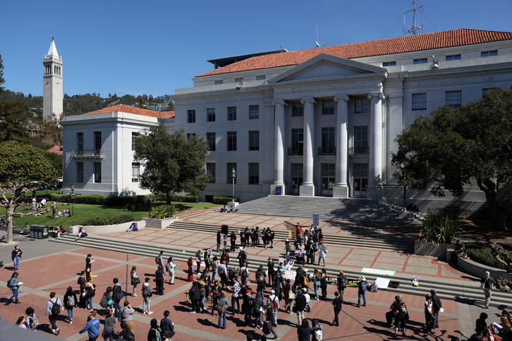 Demonstrators hold signs on the steps of Sproul Hall on the UC Berkeley campus.