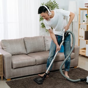 Man vacuums a rug while listening to music