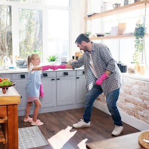 daughter and father fist bump with pink gloves and smile as they prepare to clean the kitchen