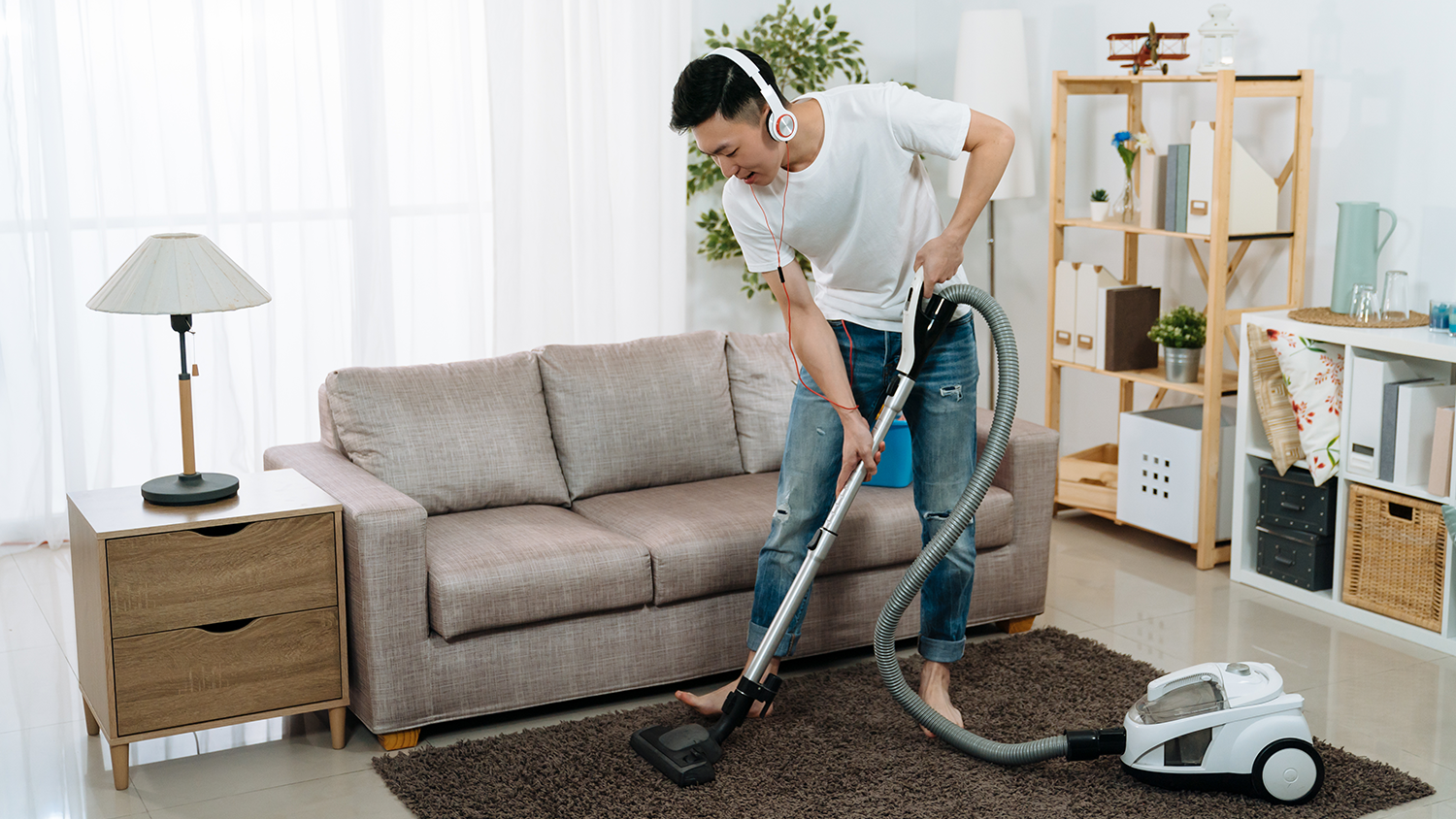 Man vacuums a rug while listening to music