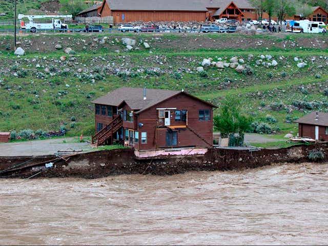 <p>In this image provided by Sam Glotzbach, the flooding Yellowstone River undercuts the river bank, threatening a house and a garage in Gardiner, Mont., on June 13, 2022</p>