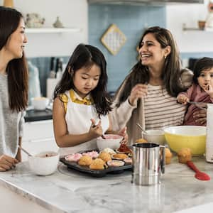 Two mothers and children cooking in a kitchen