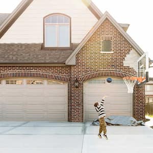 A child plays basketball in front of a garage