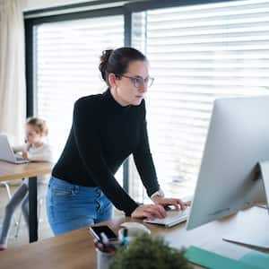 A mother working on her desktop while daughter using a laptop