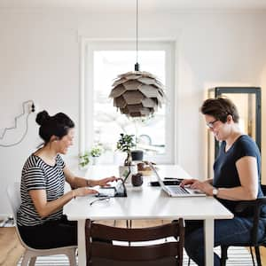 Two women working on their laptop at their living room table