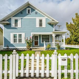 The exterior of a blue and white craftsman house with a white picket fence