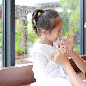 mother and daughter laughing in front of the window 