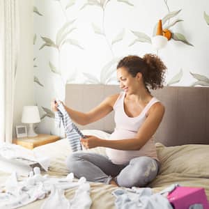 A pregnant woman in bed with beautiful wallpaper behind her