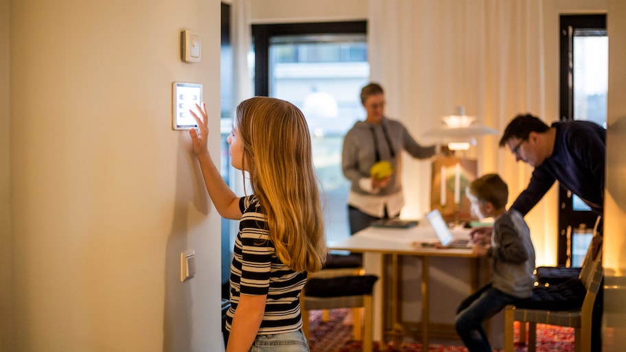 A girl operating a smart home tablet at house wall