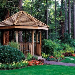 A wooden gazebo in the backyard of a house