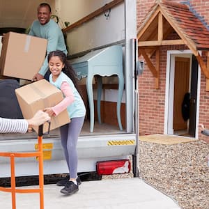 family unloading boxes from moving truck into home