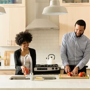 Couple in the kitchen washing and chopping veggies 