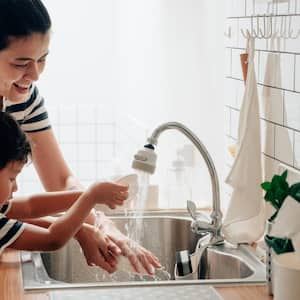 A mother with her kid doing the dishes in the kitchen