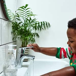 A little kid washing his hands in bathroom sink