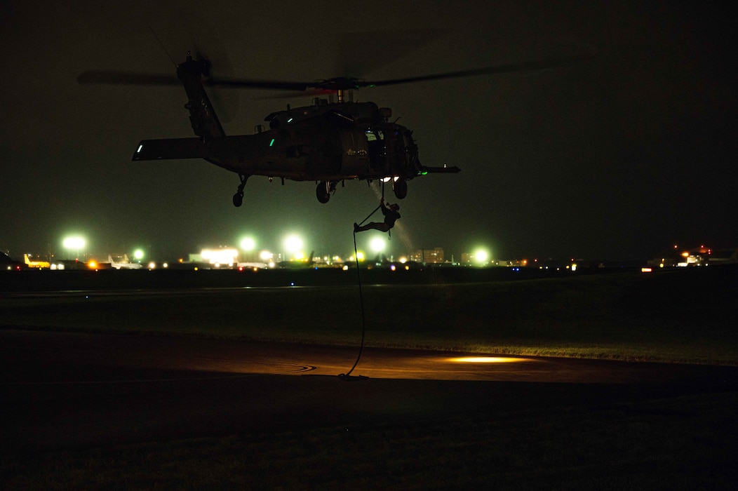 A 353rd Special Operations Support Squadron Deployed Aircraft Ground Response Element team member fast-ropes out of an HH-60G Pave Hawk