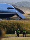 Two police officers walk near a Boeing 767 at a military base in Amesbury, Salisbury, on June 14, 2022, preparing to take asylum-seekers to Rwanda. After a last-minute intervention by the European Court of Human Rights, Britain canceled its first deportation flight.
