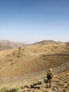 FILE - A Pakistani soldier stands guard along the border fence outside the Kitton outpost on the border with Afghanistan in North Waziristan, Pakistan Oct. 18, 2017.