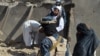 FILE - Taliban members stand guard near the rubble of a suspected Islamic State hideout following an operation against Islamic State-Khorasan, the local chapter of the jihadist group, in Kandahar, Afghanistan, Nov. 15, 2021. 