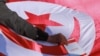 FILE - A man places a copy of the Tunisian constitution atop a Tunisian national flag during a demonstration called for by Tunisia's Islamist-inspired Ennahdha party against President Kais Saied's recent decrees, in the capital Tunis, Feb. 13, 2022.