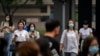 Commuters wearing face masks wait to cross an intersection in the central business district in Beijing, June 17, 2022. 