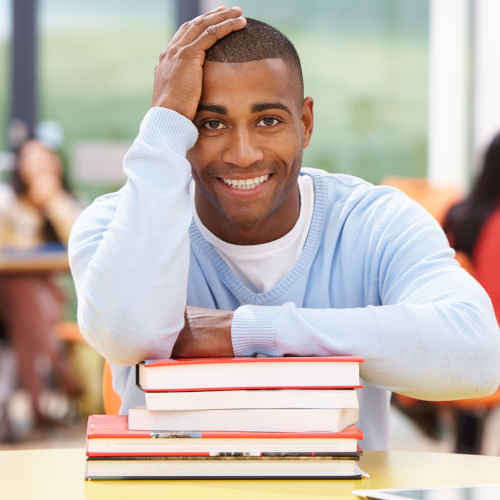 Portrait of a young man leaning on a pile of books