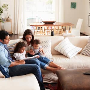 Family sitting on sofa reading a book