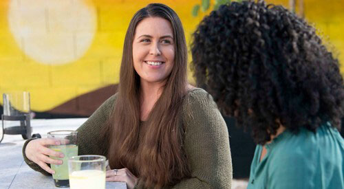 woman sitting at table, smiling at another woman