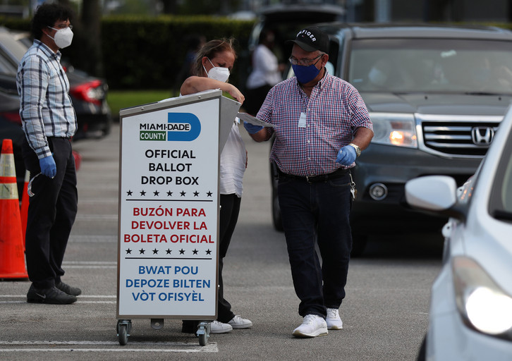 Poll workers at the Miami-Dade County Elections Department deposit peoples' mail in ballots.