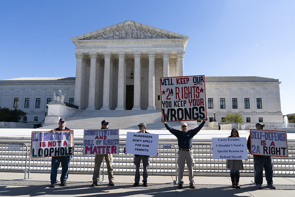 Demonstrators holding signs in support of the Second Amendment stand in front of the Supreme Court building.