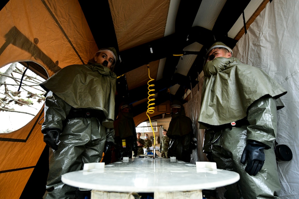 Airmen stand inside a decon shelter.