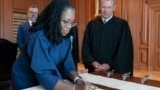 In this image provided by the Collection of the Supreme Court of the U.S., Supreme Court Justice Ketanji Brown Jackson signs the Oaths of Office at the Supreme Court in Washington, June 30, 2022, as Chief Justice of the United States John Roberts watches.