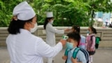 FILE - Kim Song Ju Primary school students have their temperatures checked before entering the school in Pyongyang, North Korea on June 3, 2020.