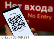 QR-код на телефоне с зашифрованной надписью "коронавирус" на фоне входа московское метро в городе Москве, Россия (2020 год). Стоковое фото, фотограф Николай Винокуров / Фотобанк Лори