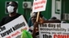 People hold signs as Ghanaians gather in the streets on the second day of protests over recent economic hardships, in Accra, Ghana, June 29, 2022.