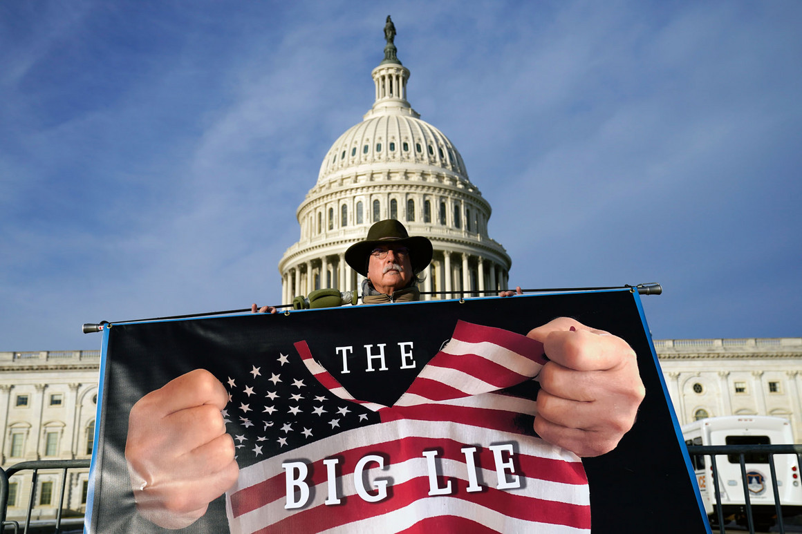 A protestor holds a &quot;The Big Lie&quot; flag in front of the Capitol. 