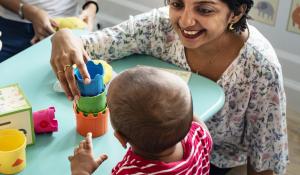 Image of South Asian teacher with child in a classroom.