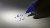 Picture of writing tips of a gel pen and a ballpoint pen lying on a piece of paper next to lines created by each pen.