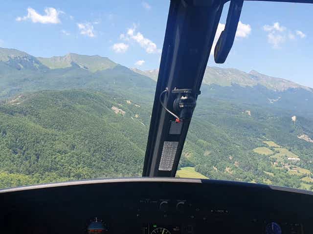 <p>An Alpine Rescue helicopter flies over the crash site in Tuscany</p>