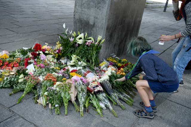 <p>People place flowers and light candles next to the Field’s shopping centre</p>