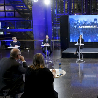 Reporters and politicians sit in a broadcasting studio.