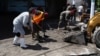 A woman and soldiers clean mud from the street after a flood caused by heavy rain in the aftermath of what is now known as Hurricane Bonnie, in Ilopango, El Salvador, July 3, 2022. 