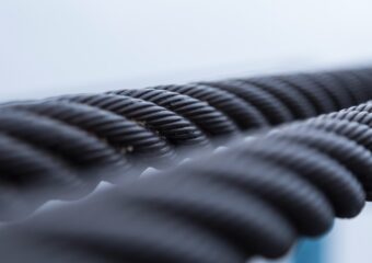 Closeup of steel cables, against a neutral color background.