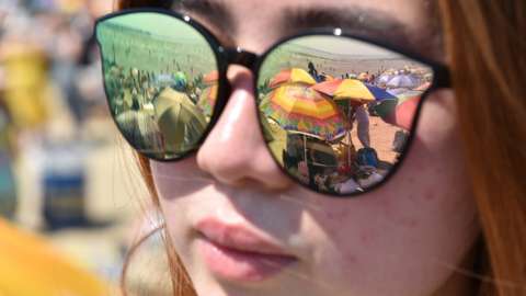 Reflection of the beach through a woman's sunglasses