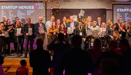 A crowd of people next to a screen that reads "Startup Heroes"