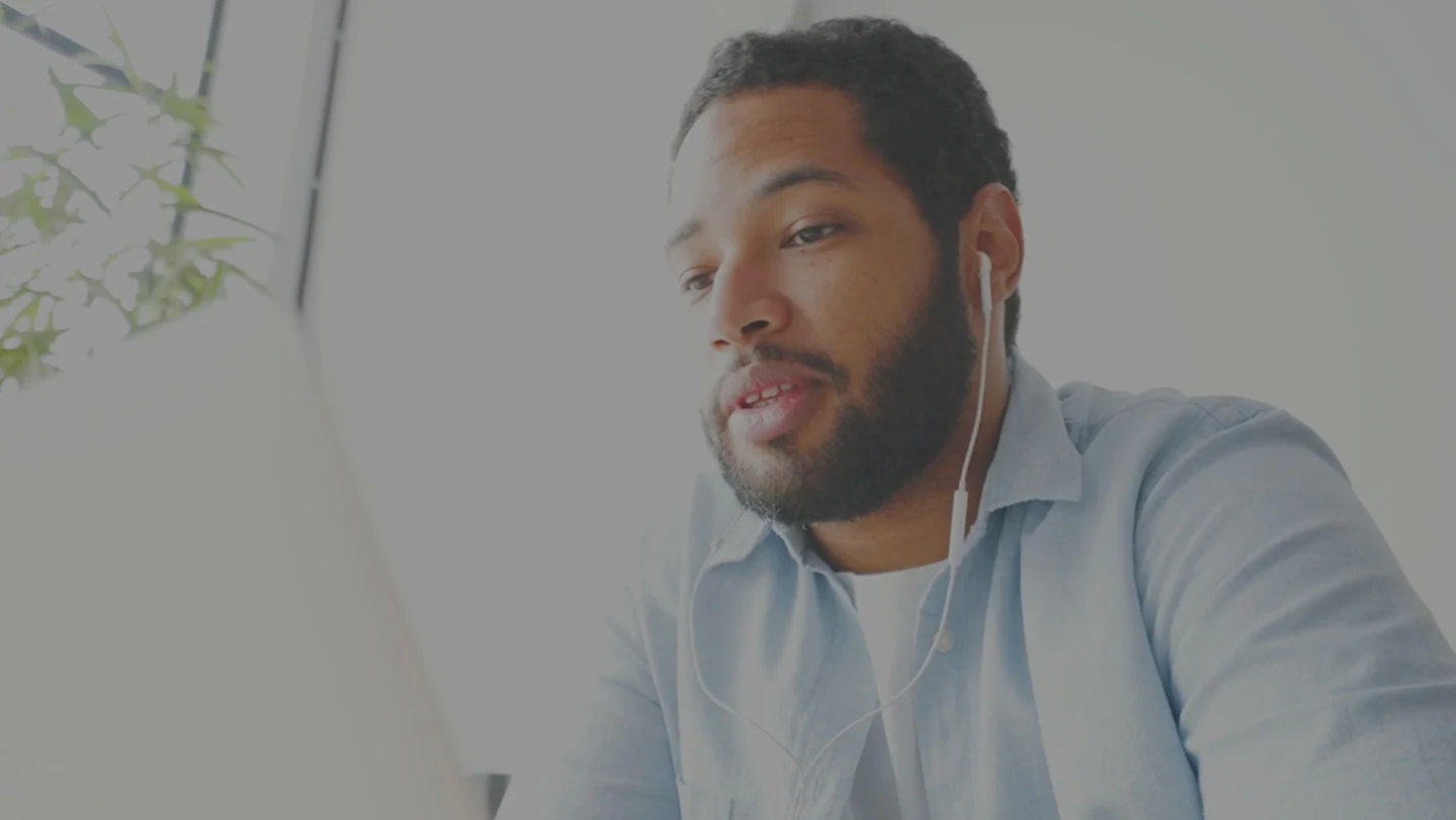 Person wearing ear buds while looking at laptop