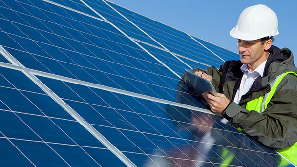 Person looking at electronic tablet surrounded by solar panels