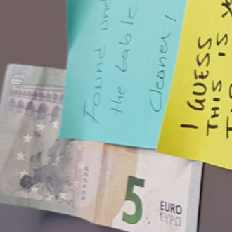 Close-up of a five-euro bill and post-it notes on a table.