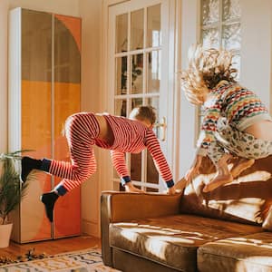 Kids bouncing on a brown leather sofa