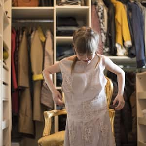 A little girl plays dress-up in a walk-in closet 